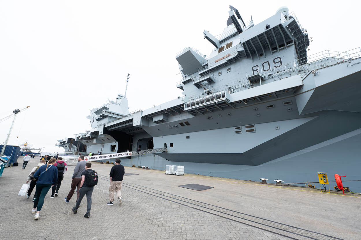 Bemanningsleden lopen met tassen op hun rug naar de loopplank.