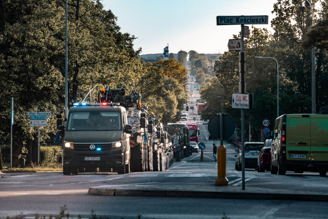 Diverse militaire voertuigen rijden in een lint door een Pools dorp.