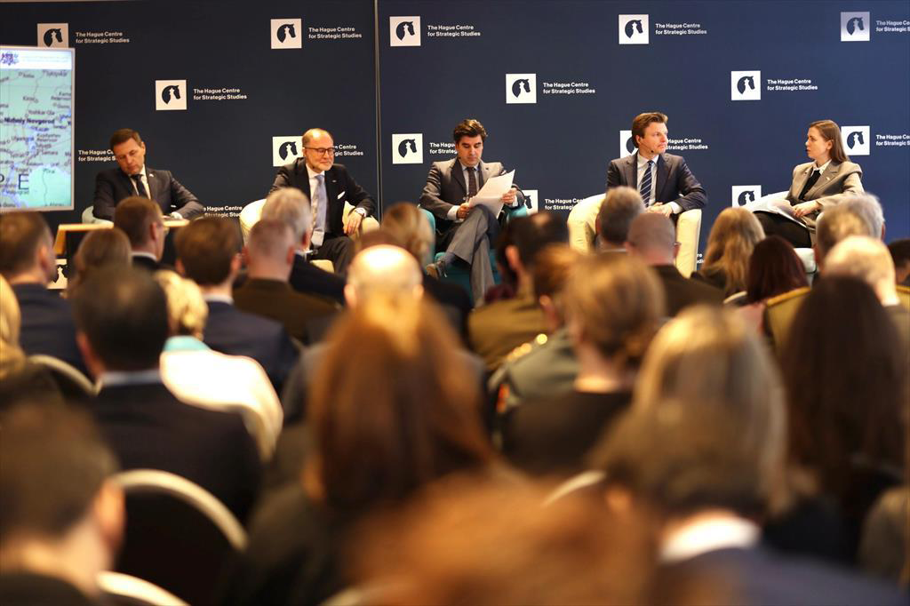 Ministers zitten op stoelen tijdens een paneldiscussie.