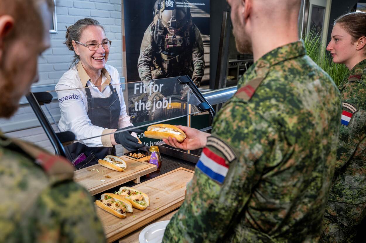 een Parestomedewerker die een broodje overhandigt aan een klant.