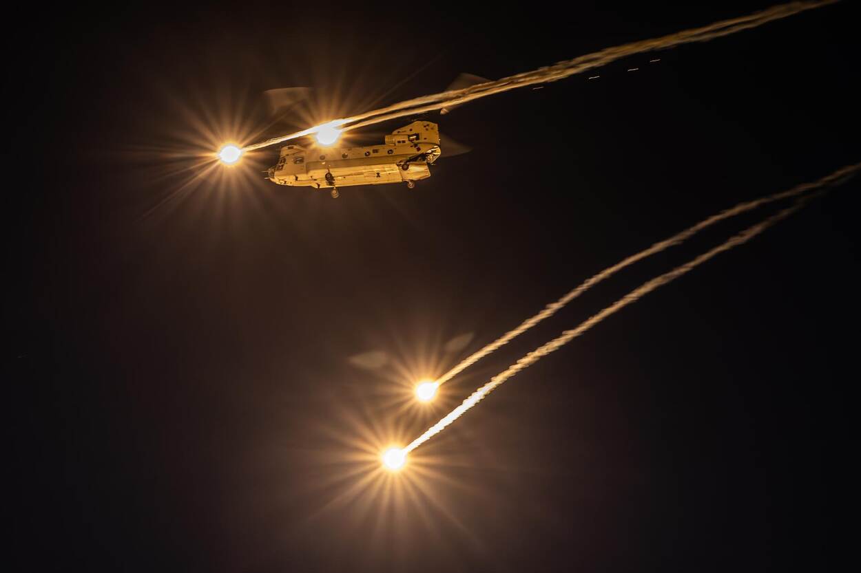 Een Chinook transporthelikopter werpt lichtspoormunitie af tijdens een avondoefening.