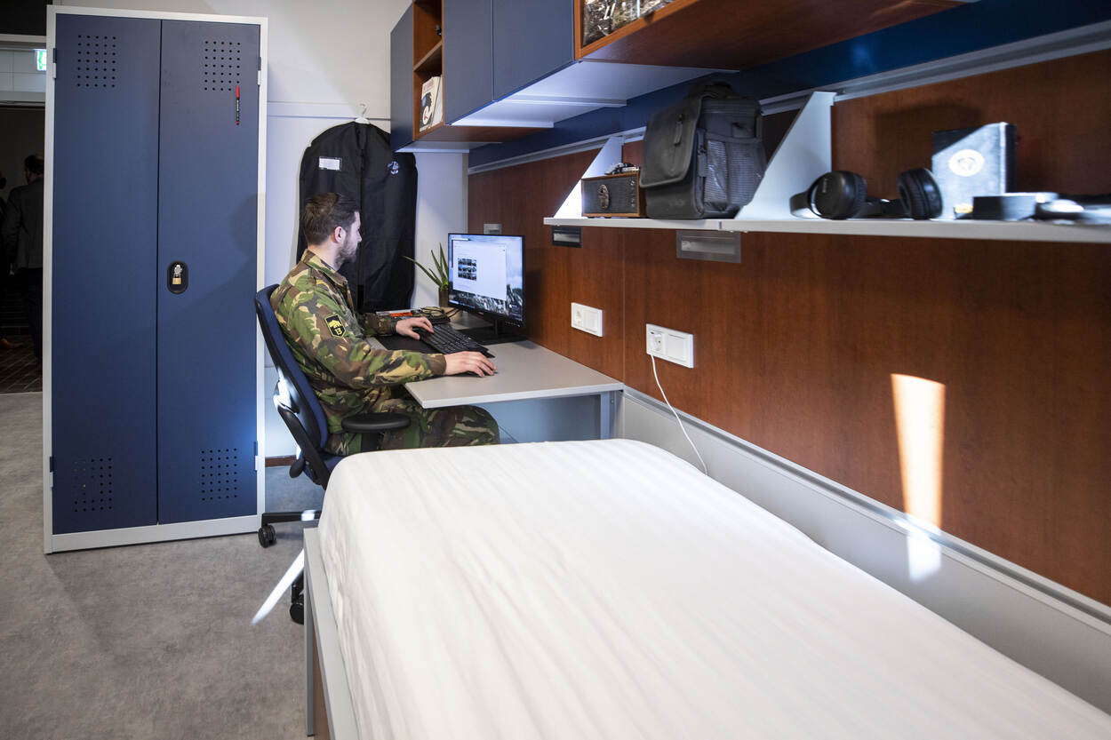 Een militair zit aan z’n bureau in zijn legeringsgebouw.