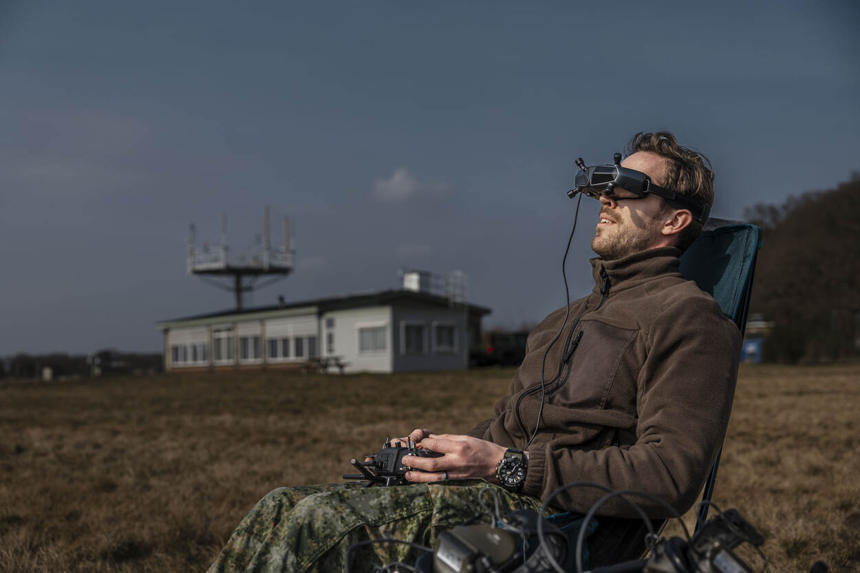 Een luchtmachter bestuurt een drone met een speciale bril op zijn hoofd.