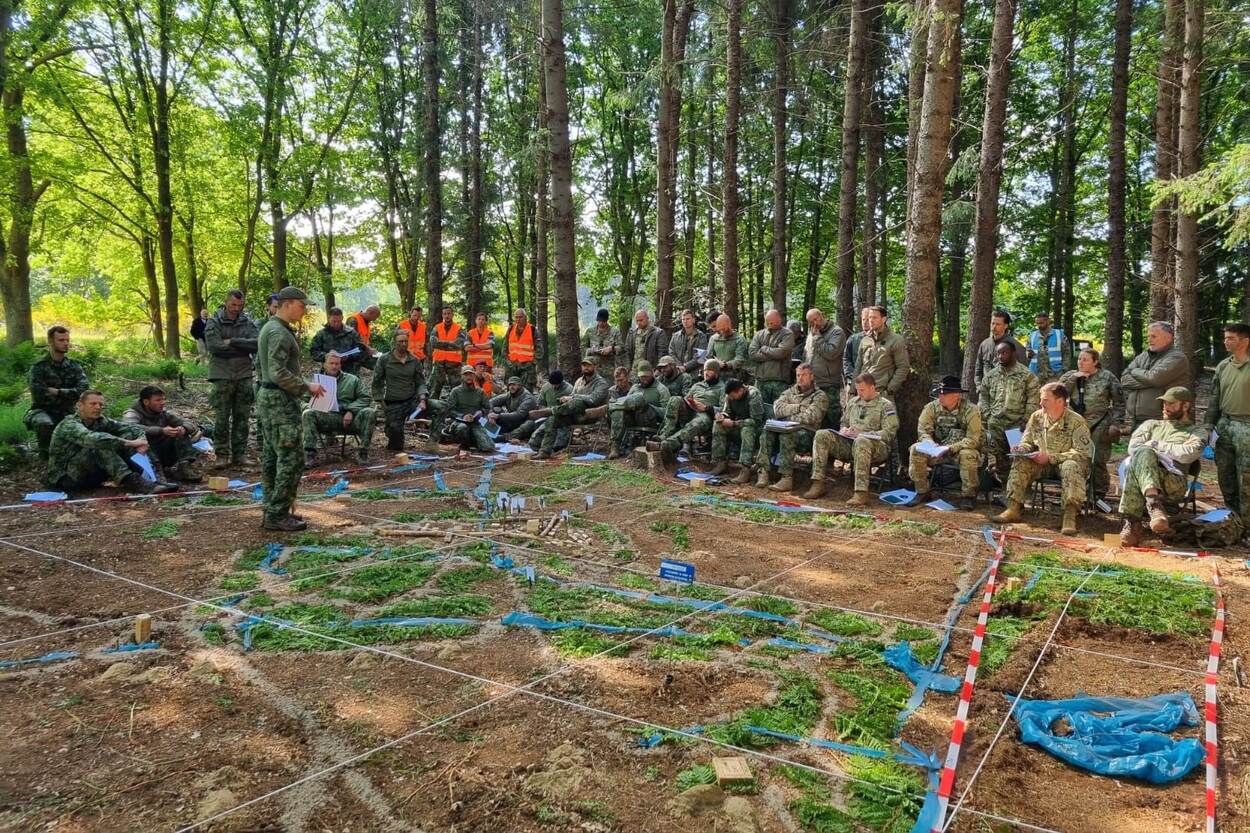 een grote maquette in het bos met daaromheen veel militairen.