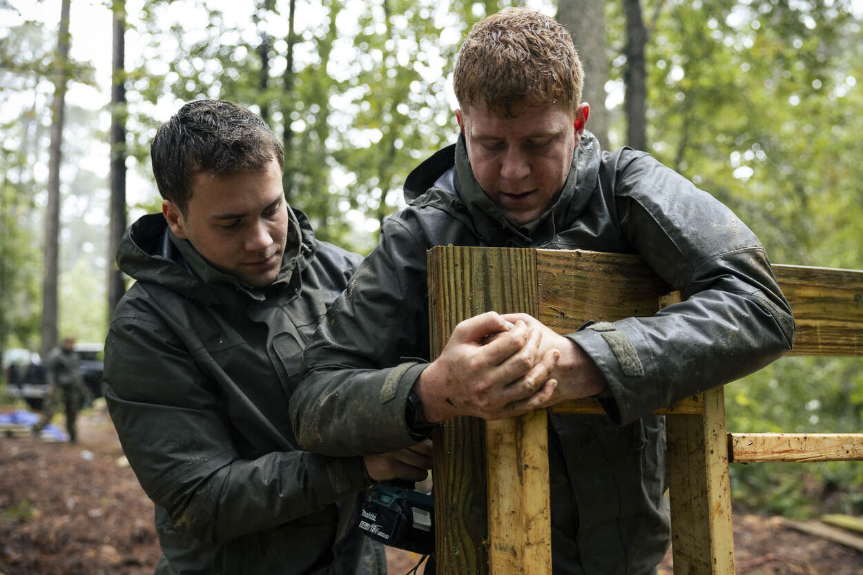 Twee militairen timmeren aan een luik in het bos