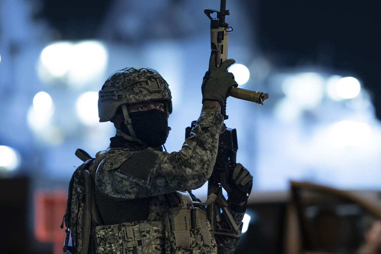 Een militair houdt zijn wapen omhoog.