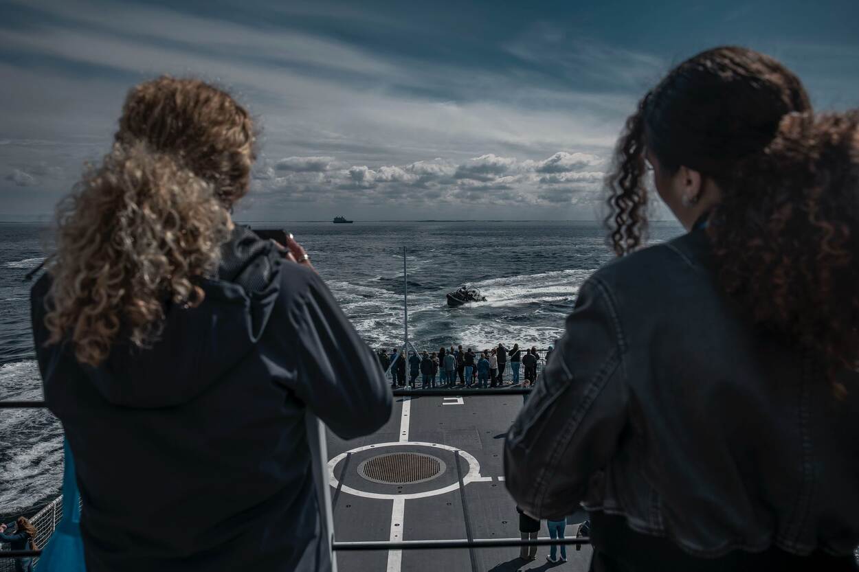 2 meiden kijken uit op het achterdek en de zee en maken foto’s van een FRISC.