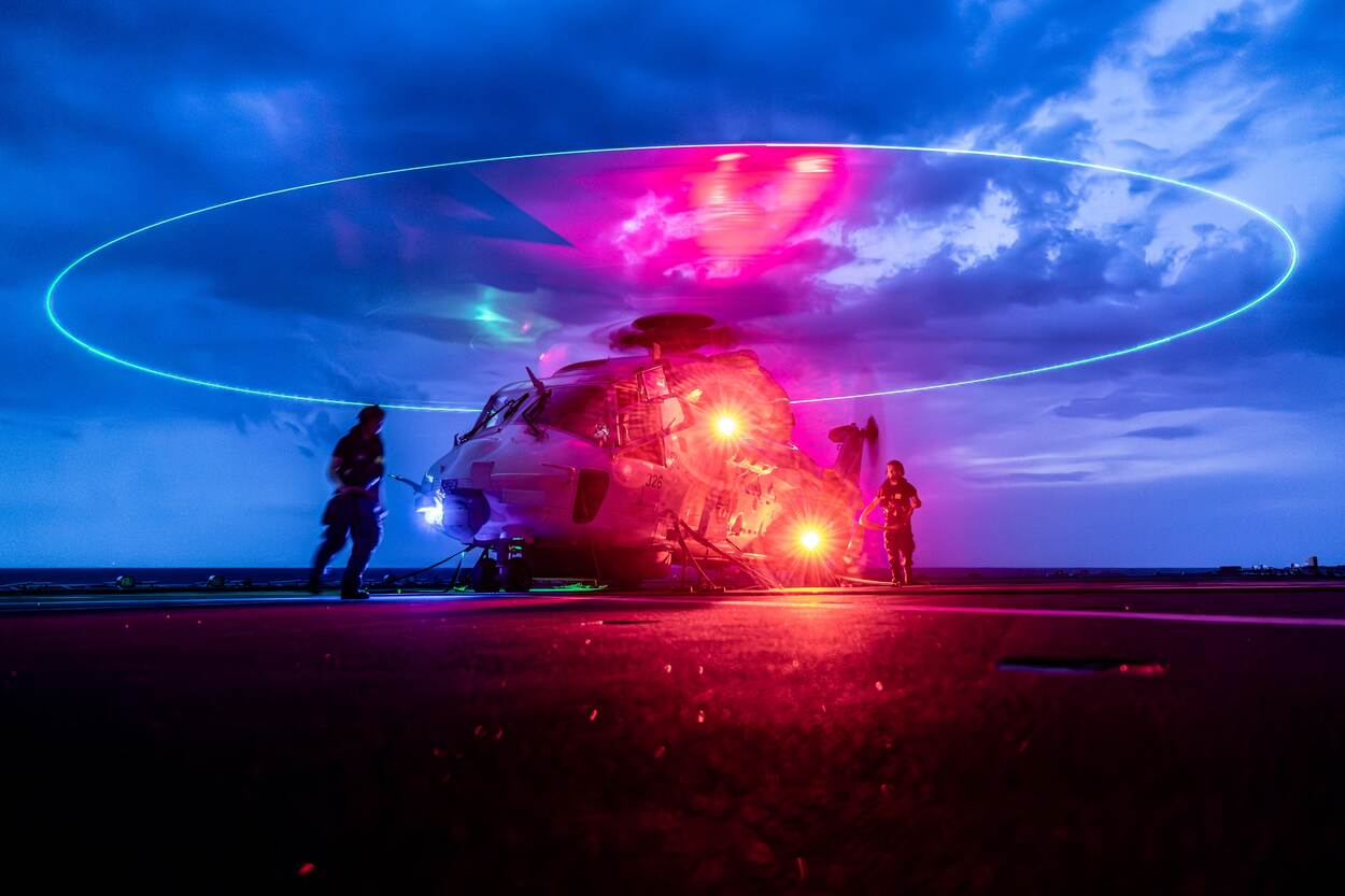 Een NH90 staat in de schemering te draaien op het helidek.