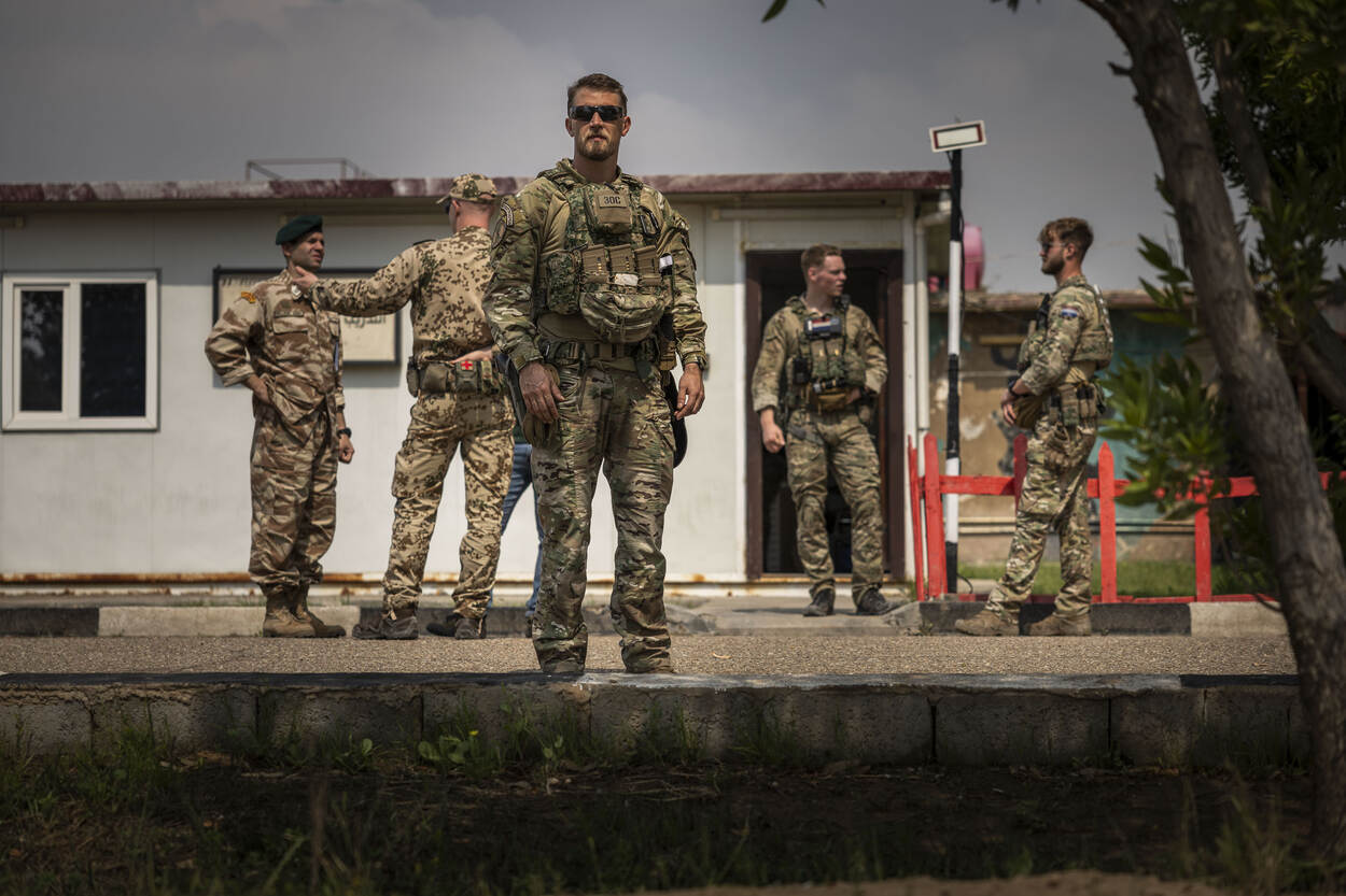 Nederlandse militair met zonnebril kijkt recht vooruit met op de achtergrond vaag enkele militairen.
