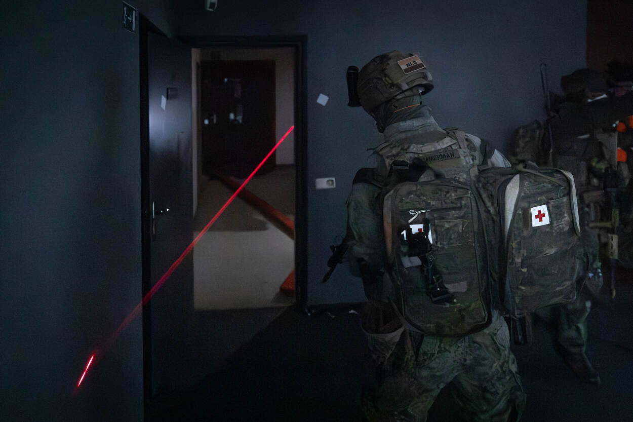 Een rode laserstraal priemt door een donkere ruimte, duidelijk zichtbaar voor de medische collega.