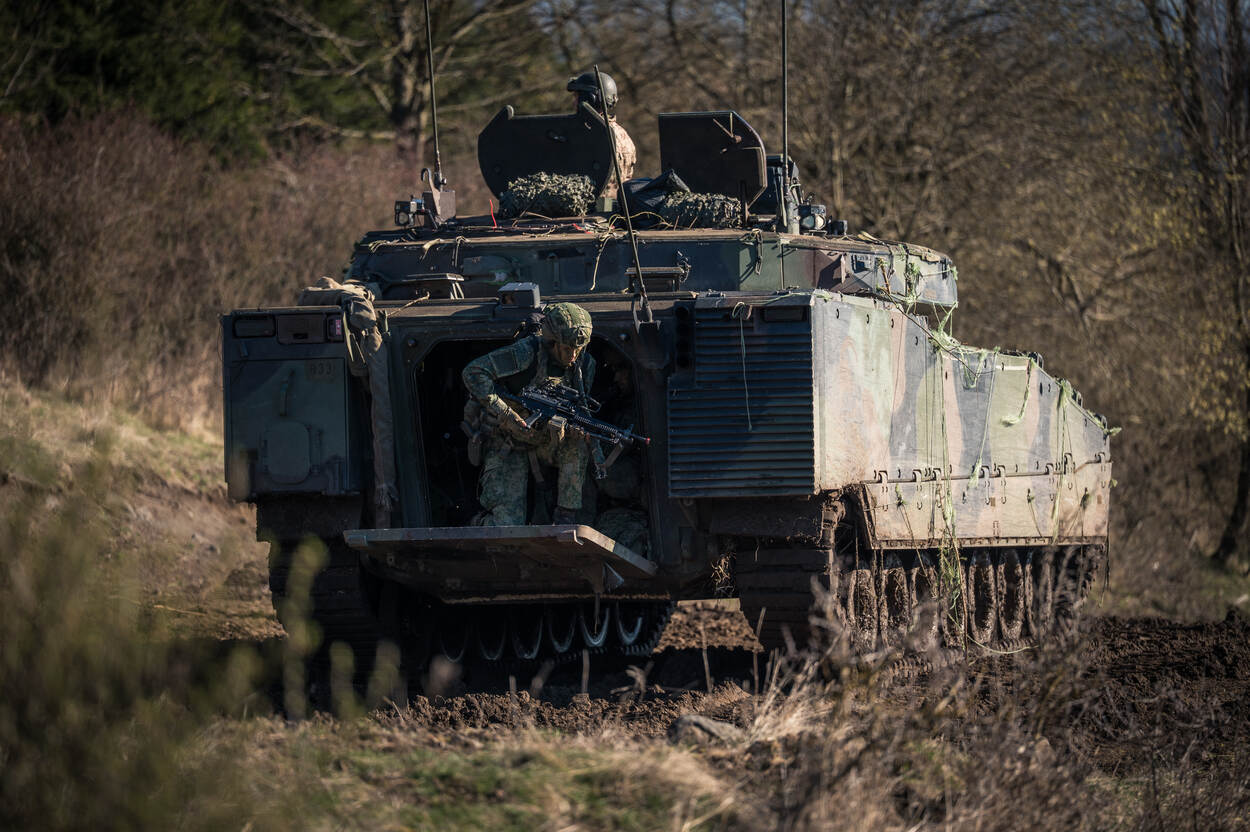 Een militair stijgt uit uit een CV90.