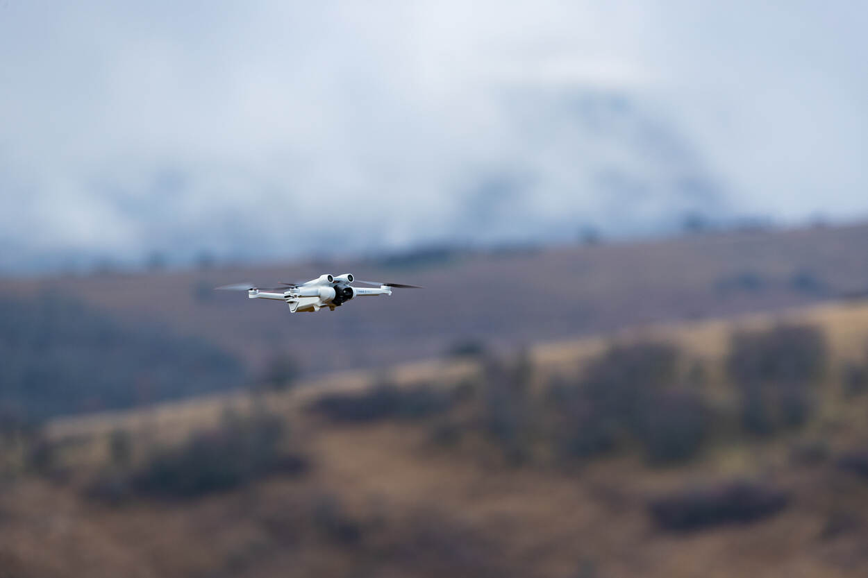 Op de ene foto vliegt een drone door de lucht. Door de beweging, is de achtergrond vaag. Op de andere foto zijn twee militairen te zien, met een groot langwerpig apparaat in handen. De rookpluimen komen uit de loop van de zwarte dronevanger.