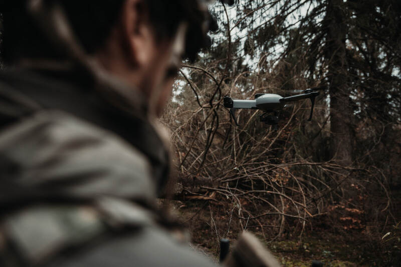 Een militair van de achterzijde bezien. Voor hem vliegt een drone.