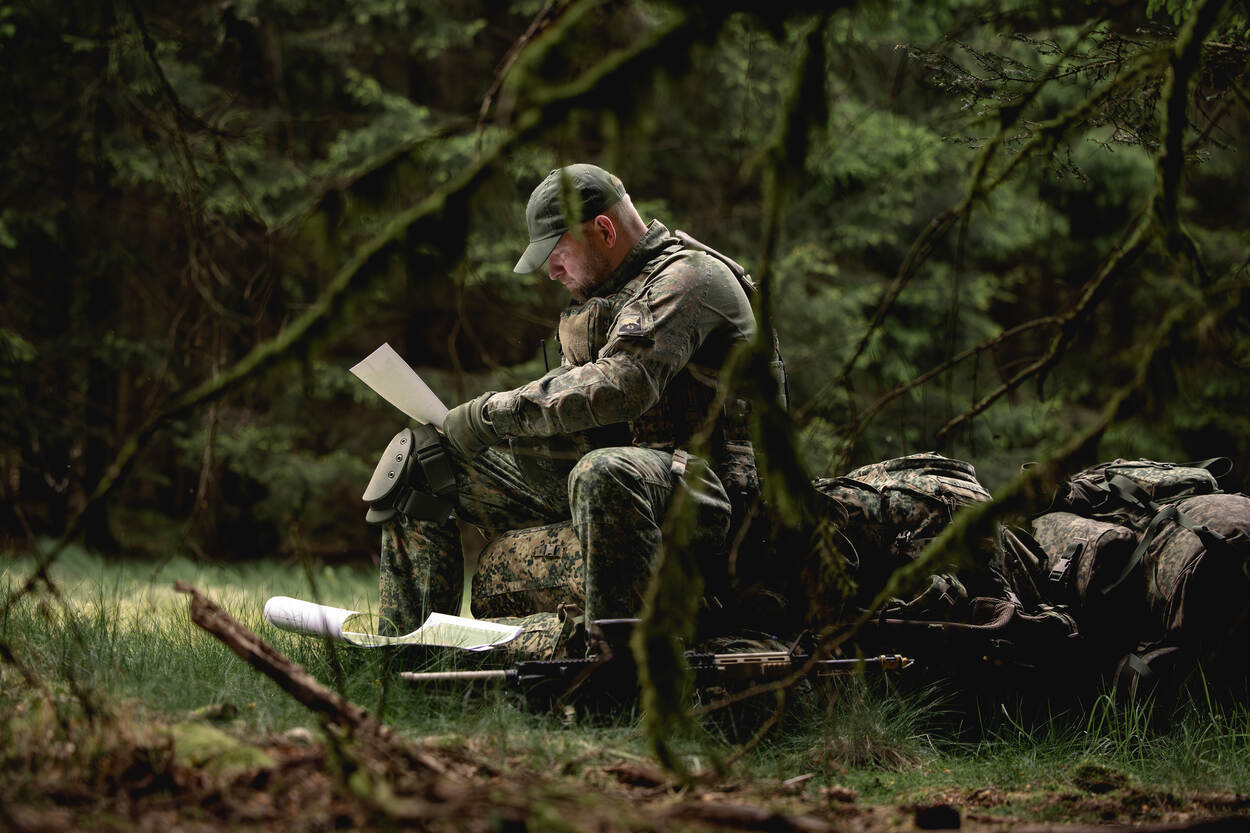 Zittende kaartlezende militair.
