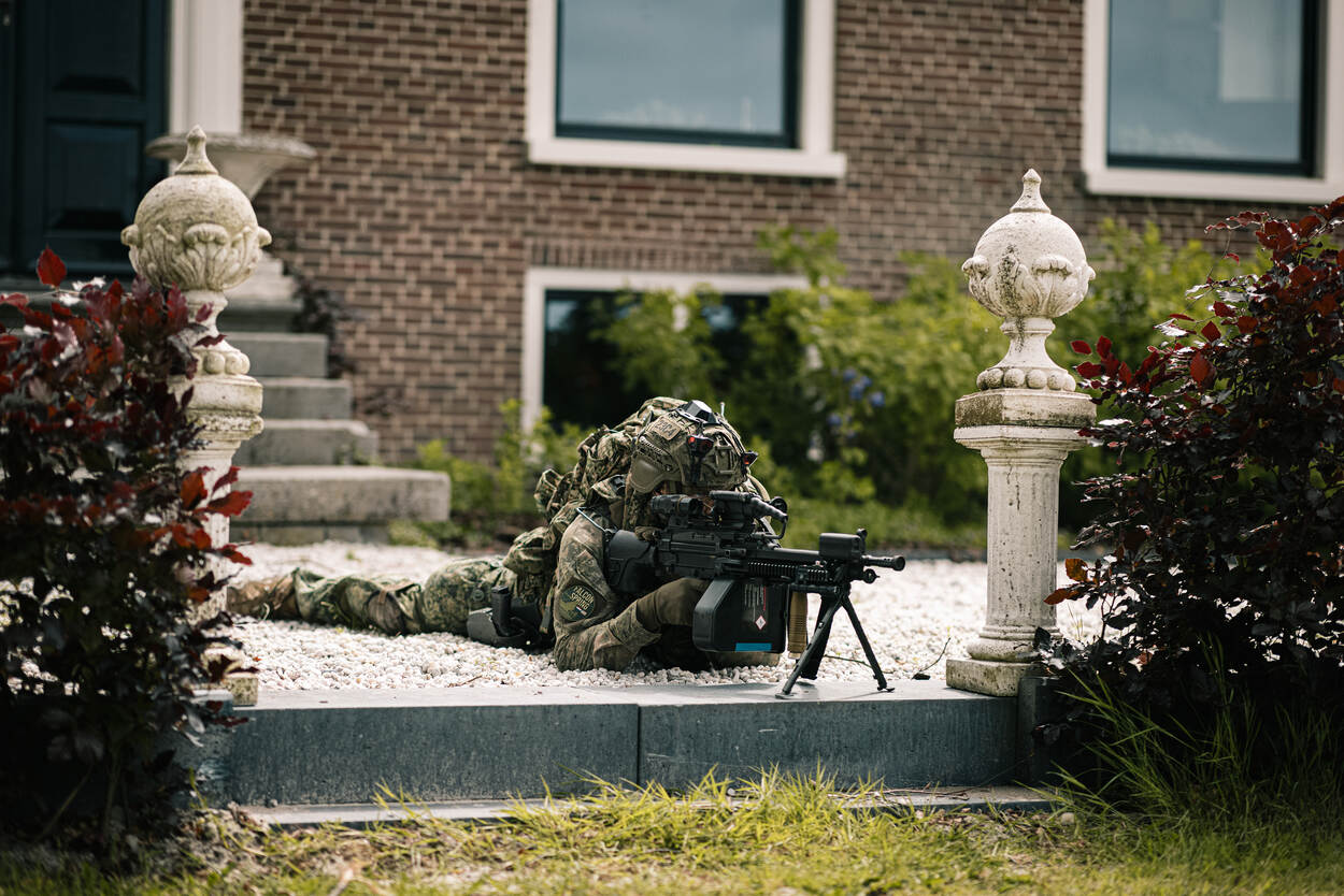 Een militair op zijn buik achter een wapen.
