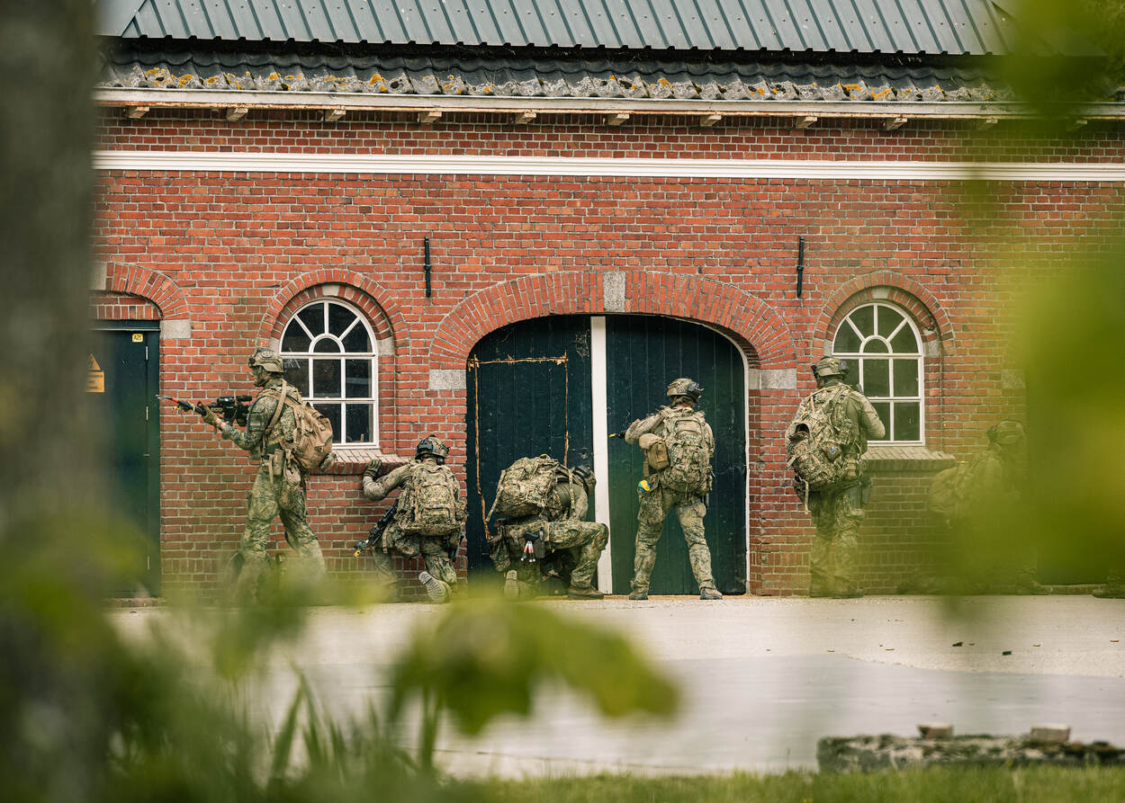 Militairen dringen een boerderij binnen.