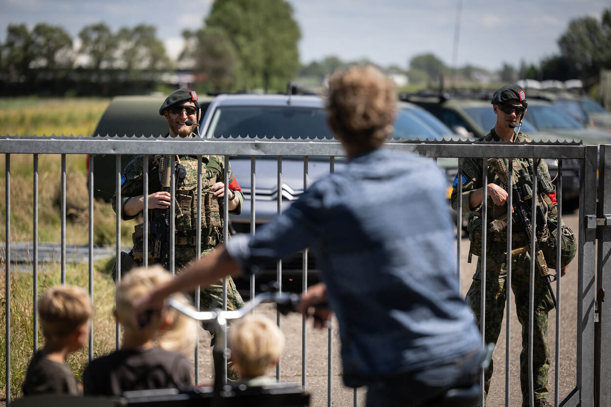 Nieuwsgierige mensen melden zich bij de poort van het terrein.
