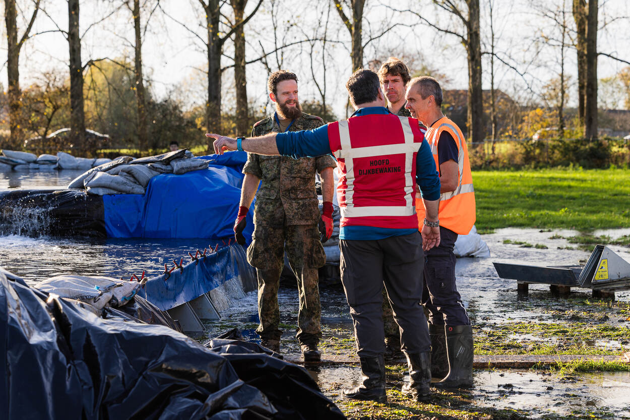 4 mensen van wie 1 in militaire outfit overleggen bij een fictieve dijkdoorbraak.