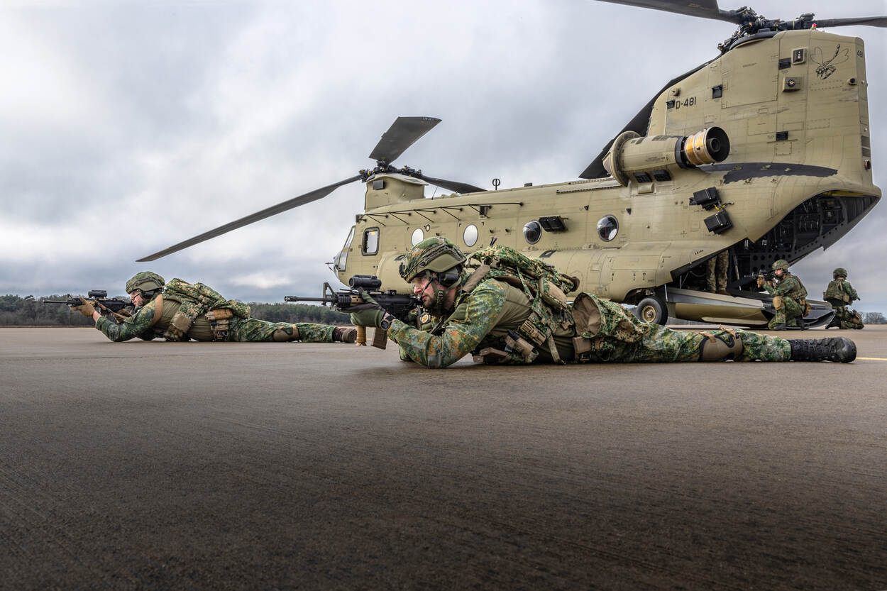 Een lid van een AMPT bewaakt liggend met zijn geweer een Chinook.