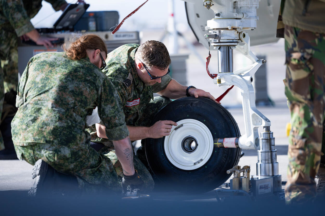 grondpersoneel inspecteert een wiel van het landingsgestel.