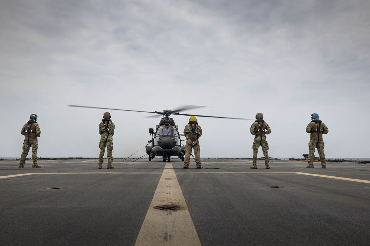 De Cougar op het helidek van Zr.Ms. Karel Doorman met leden van de boordvliegtuigploeg op de voorgrond.