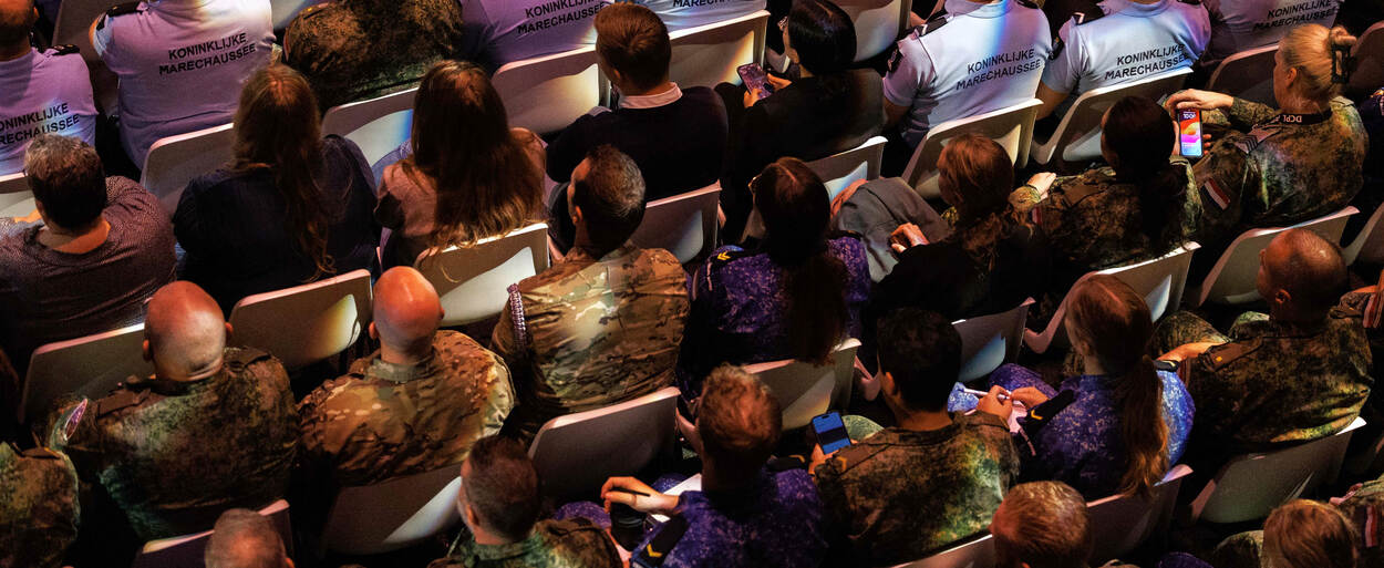 Een rij deelnemers in de zaal van bovenaf gezien.