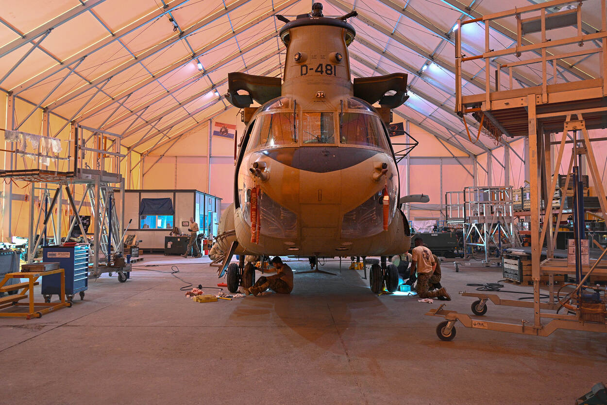 Overzichtsfoto van de tijdelijke hangar met daarin een Chinook en personeel dat er aan werkt.