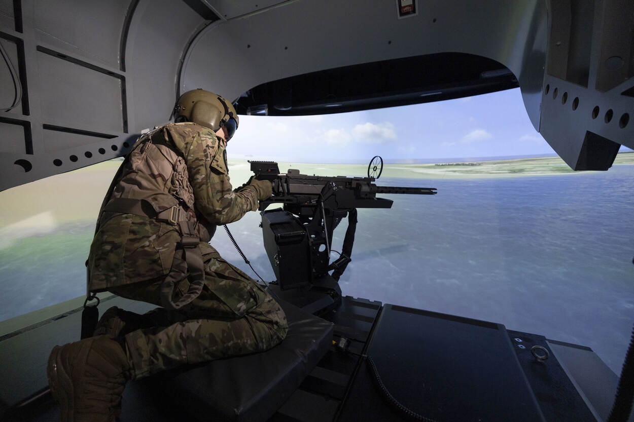 Sergeant Michiel in de nagemaakte achterklep van een Chinook, van waaruit hij met het wapen in de hand uitkijkt over de gesimuleerde wereld.