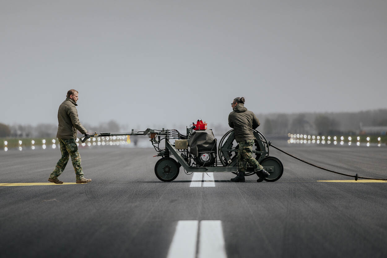 Twee mannen rollen de barrier cable uit over de startbaan.