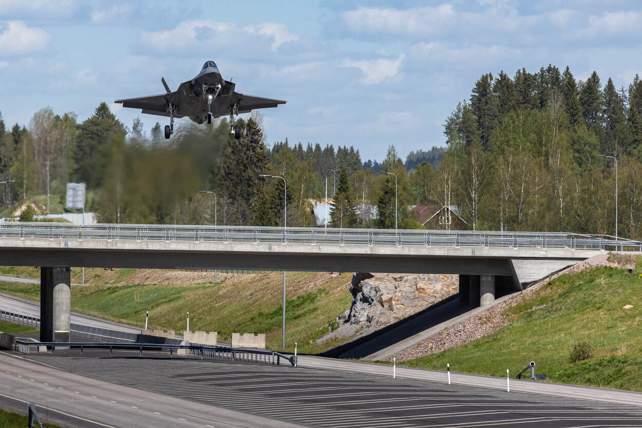 Een F-35 vliegt vlak boven een viaduct en snelweg.
