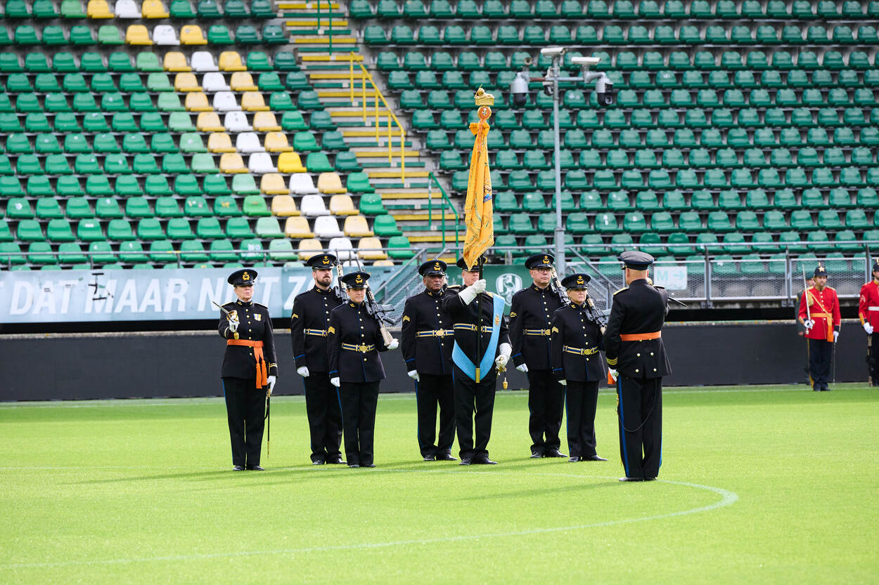 De vaandelwacht staat opgesteld in het stadion van ADO Den Haag. Daarvoor de commandant met een sabel in zijn hand.