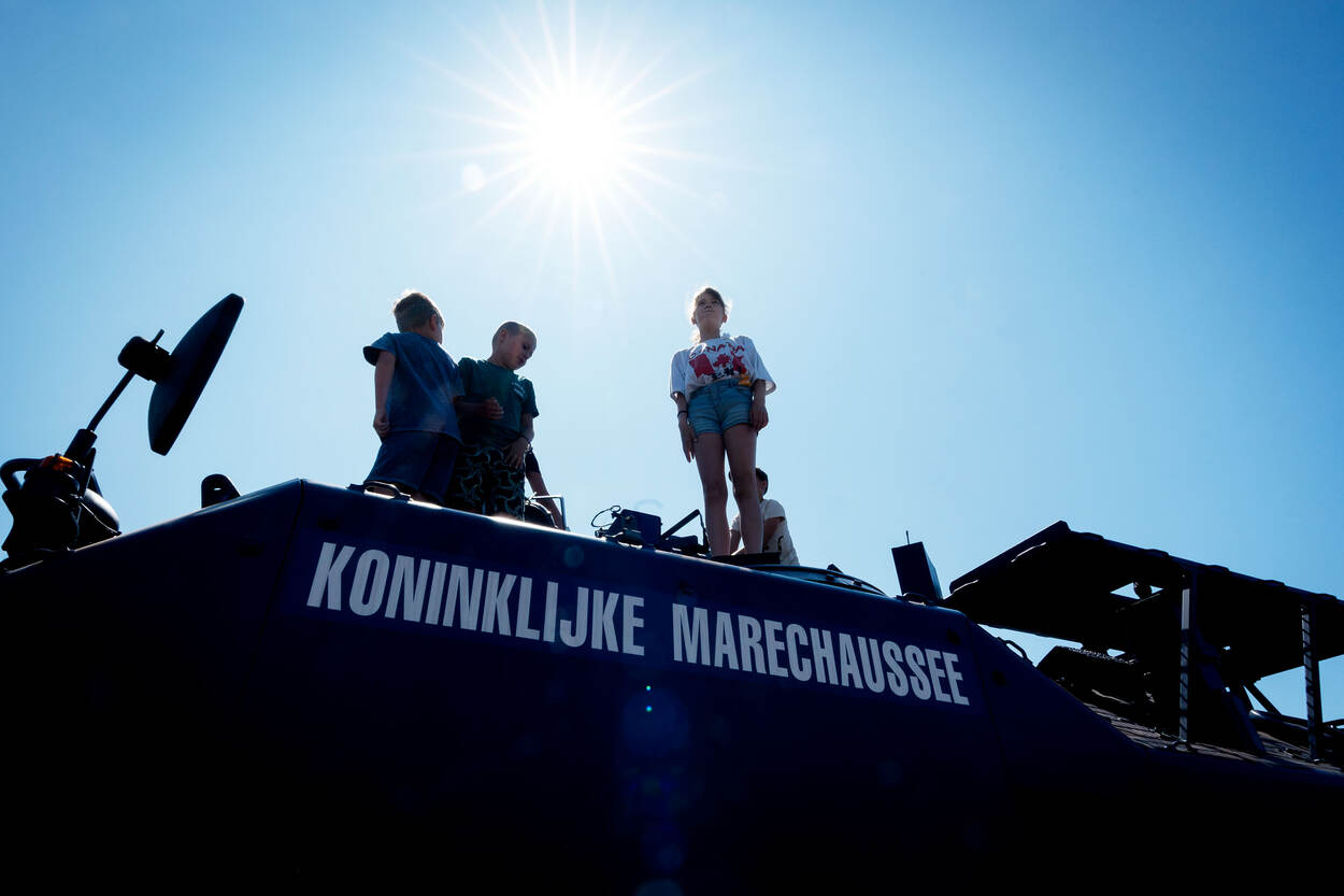 Kinderen beklimmen een YPR van de Marechaussee.