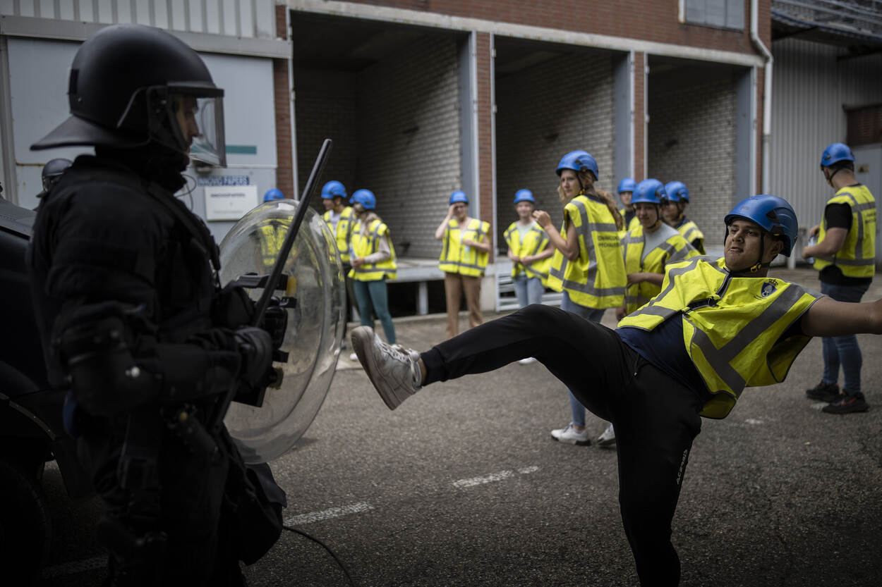 Een demonstrant maakt een schoppende beweging naar de ME.
