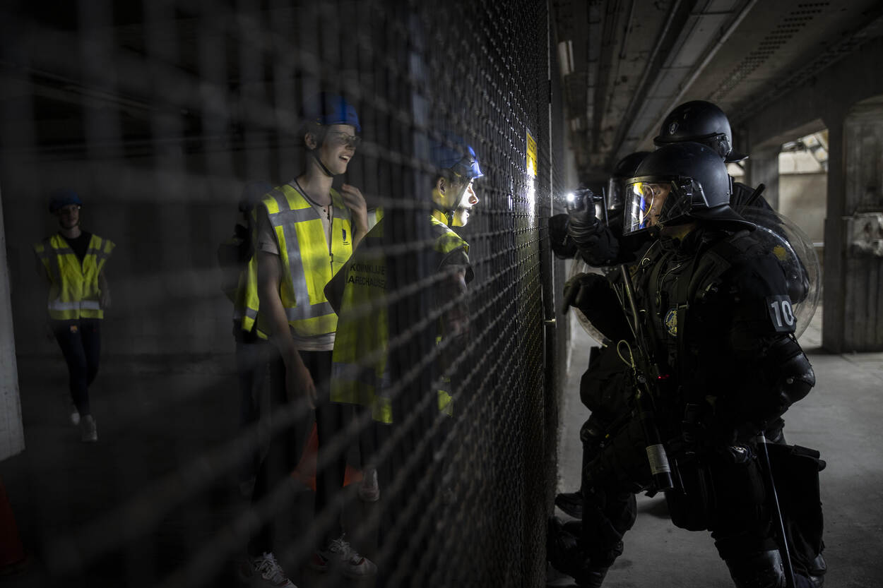 De demonstranten staan achter een hek. De ME staat aan de andere zijde.