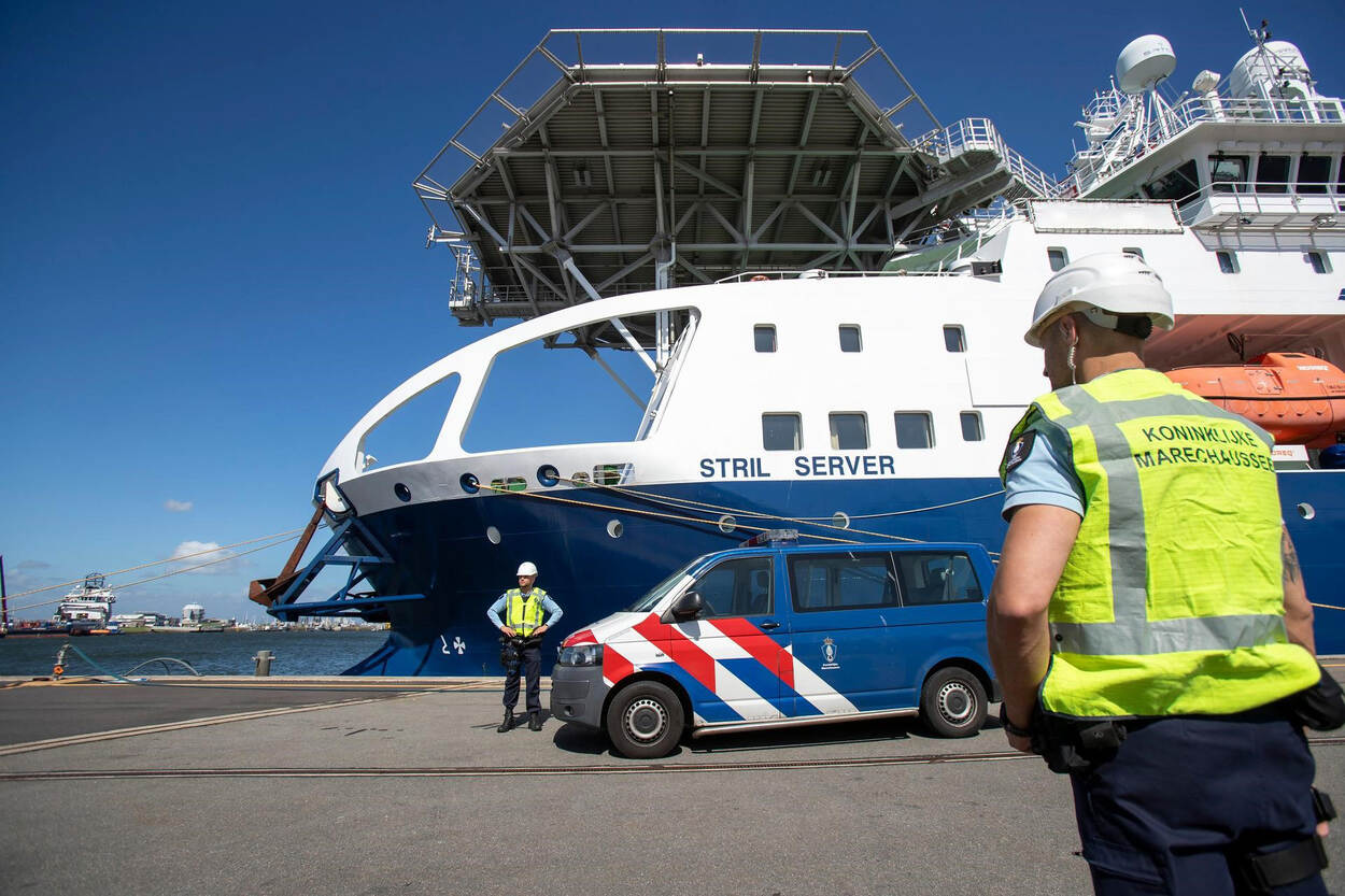 Een marechausseebusje in combinatie met een vrachtschip.