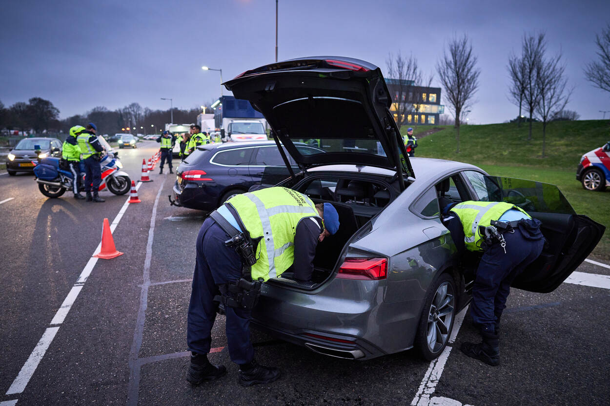 Twee marechaussees doorzoeken een auto.