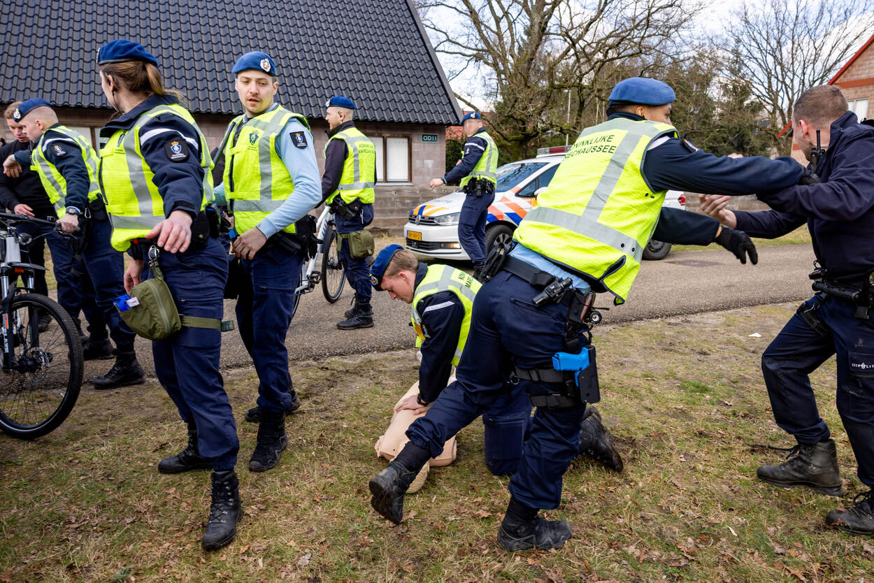 Terwijl een collega oefent met reanimeren op een dummy, maken andere collega’s ruimte door de menigte op afstand te houden. Een van hen duwt een omstander weg.