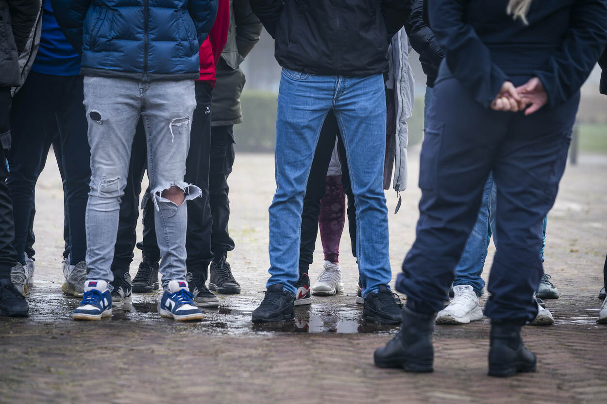 Jonge mensen worden door een KMar-medewerker toegesproken.