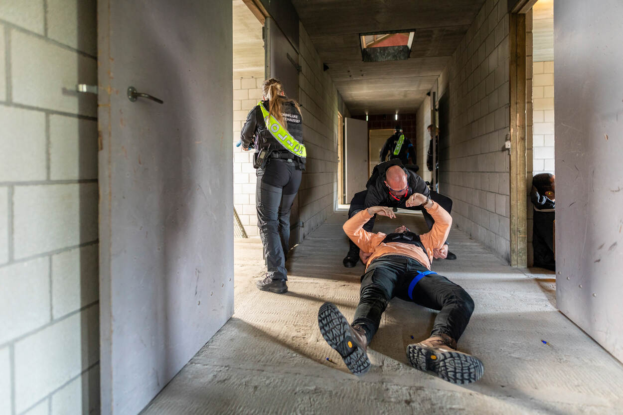 Persoonsbeveiligers slepen een gewonde Te Beveiligen Persoon door een gang.