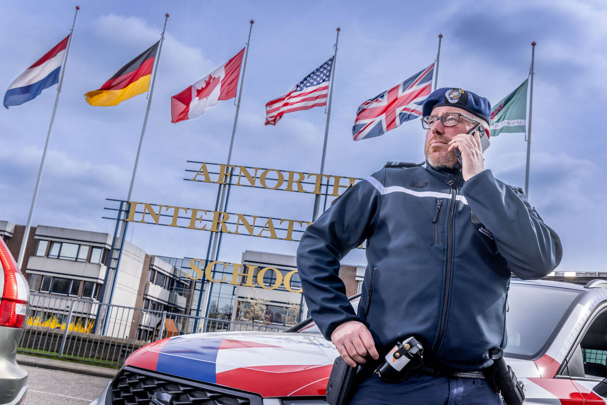 Wijkopperwachtmeester Bas poseert voor de internationale school AFNORTH waar honderden kinderen van NAVO-militairen les krijgen.