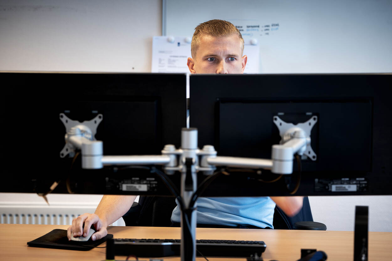 Machiel zit achter twee computerschermen te werken.