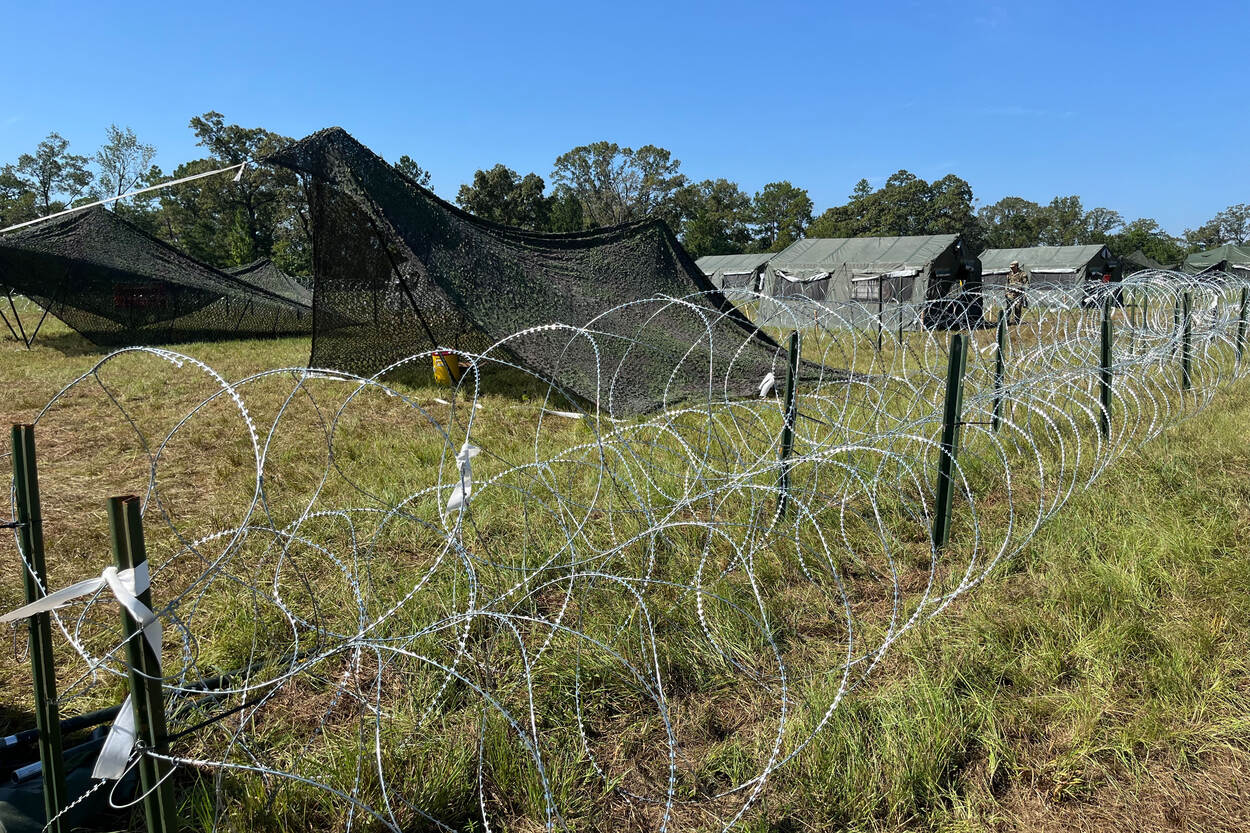 Tentenkamp omringd door prikkeldraad en een militair