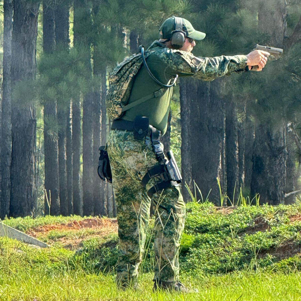 een militair gebruikt zijn wapen op een heide tussen de bomen