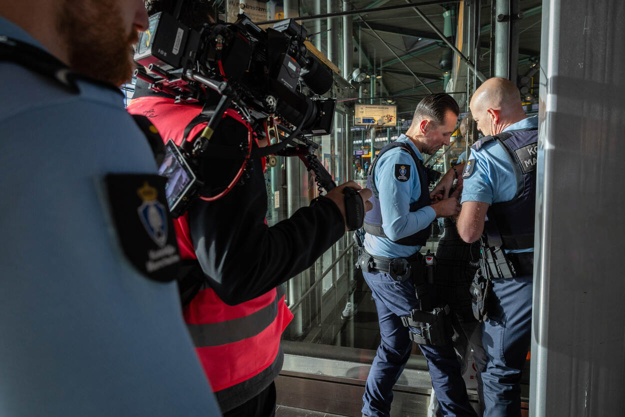 Marechaussees houden verdachte aan, worden gefilmd.