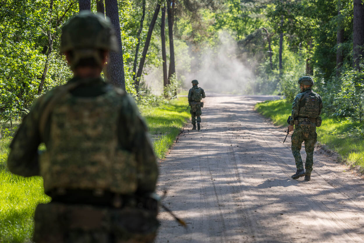 Militairen op de rug gezien tijdens een oefening in het bos.