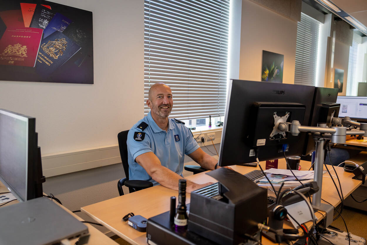 Documentdeskundige Adjudant Raijmond lachend achter zijn computer.