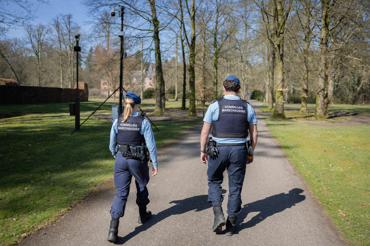 marechaussees lopen door een park langs een camera met radar.