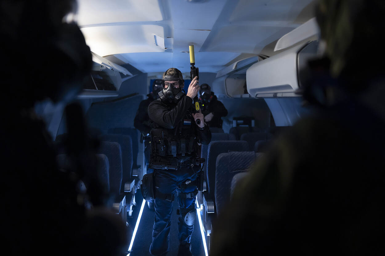 Gemaskerde GBB’ers betreden met getrokken wapen een vliegtuig.