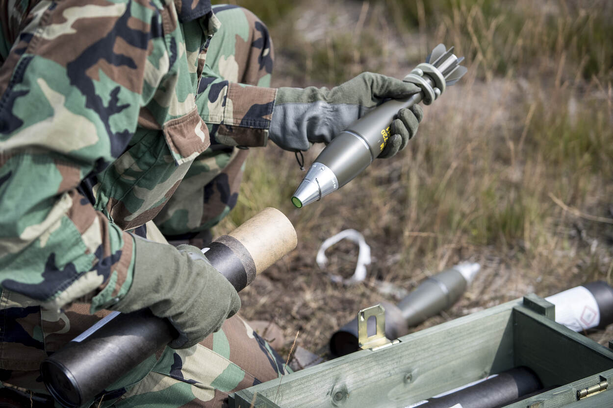 Militair haalt mortiergranaat uit kartonnen verpakking.