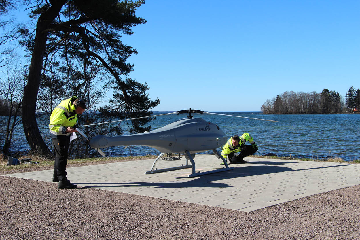 Technici bereiden een vlucht van de helikopterdrone voor in Zweden bij een meer.